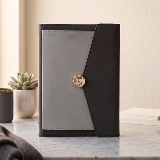 A closed A5 PU leather planner binder in charcoal and light grey with a marble-and-gold magnetic clasp.
