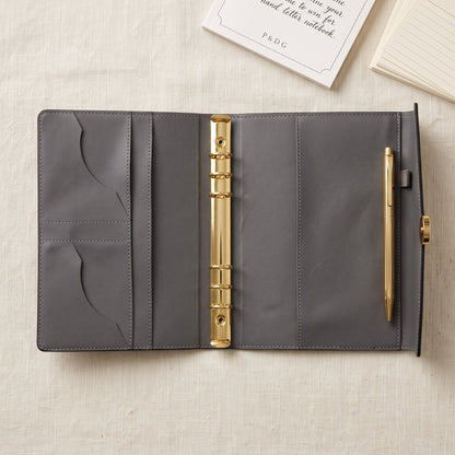 Open Noir A5 binder showing the six-ring gold mechanism and functional interior storage pockets.